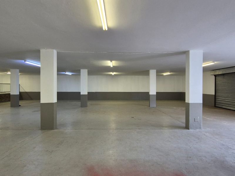 Spacious industrial garage area featuring concrete flooring, structural support columns, and a large roller shutter door for vehicle or storage access.