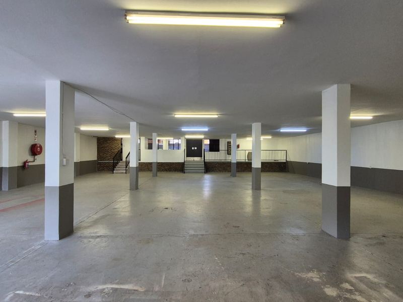 Spacious open-plan industrial garage area featuring concrete flooring, structural support columns, and integrated fluorescent lighting.