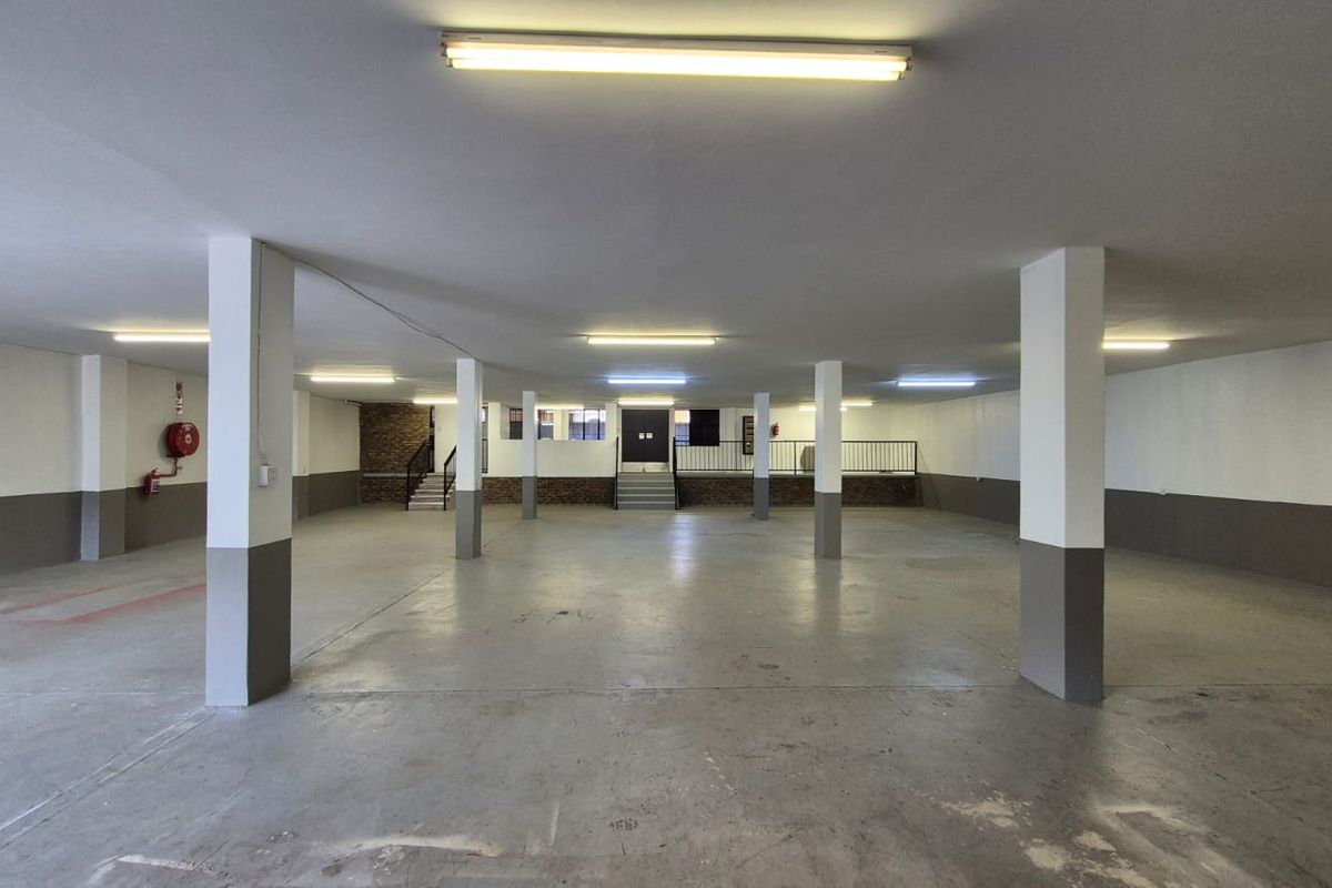 Spacious open-plan industrial garage area featuring concrete flooring, structural support columns, and integrated fluorescent lighting.