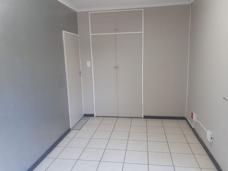 A vacant office space featuring tiled flooring, built-in cupboards, and neutral wall finishes, suitable for a professional workspace.