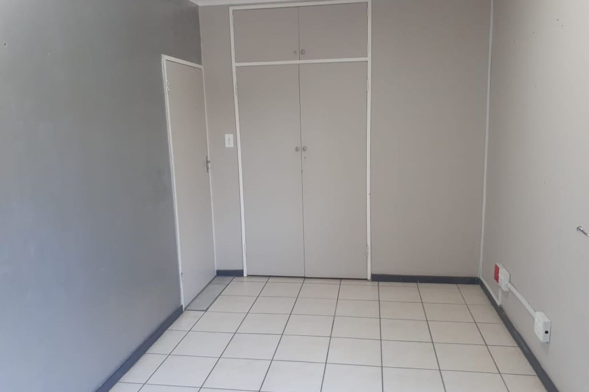 A vacant office space featuring tiled flooring, built-in cupboards, and neutral wall finishes, suitable for a professional workspace.