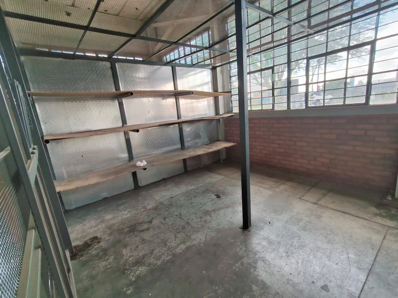 Industrial utility space featuring exposed brick walls, steel-framed windows, concrete flooring, and built-in metal shelving units.
