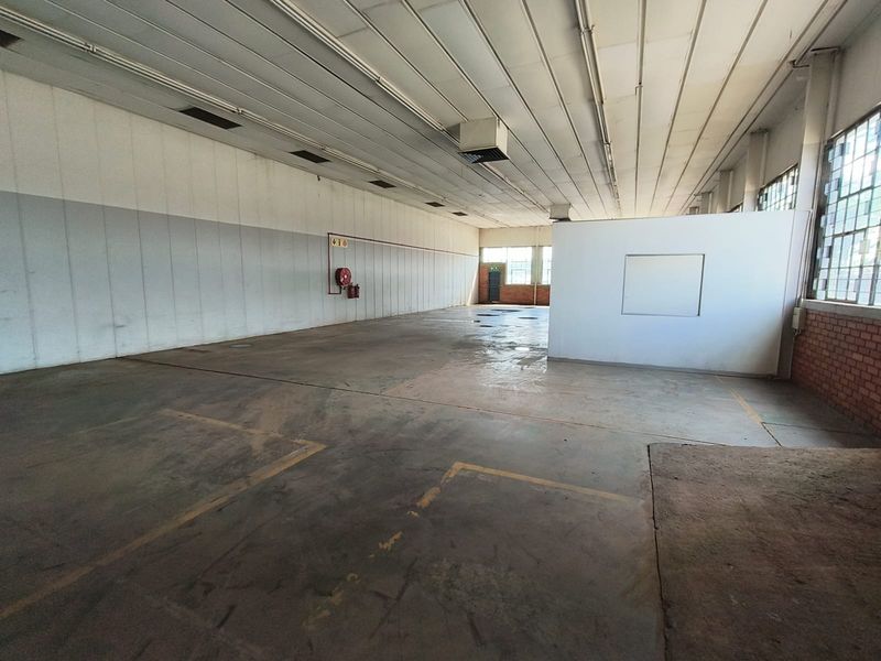 Spacious industrial utility area featuring concrete flooring, high ceilings, and large steel-framed windows, suitable for storage or workshop use.