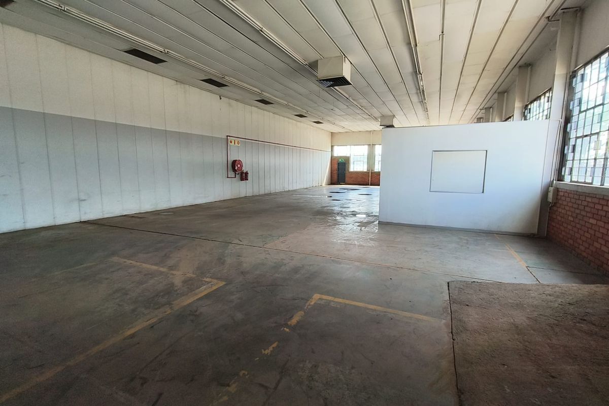 Spacious industrial utility area featuring concrete flooring, high ceilings, and large steel-framed windows, suitable for storage or workshop use.