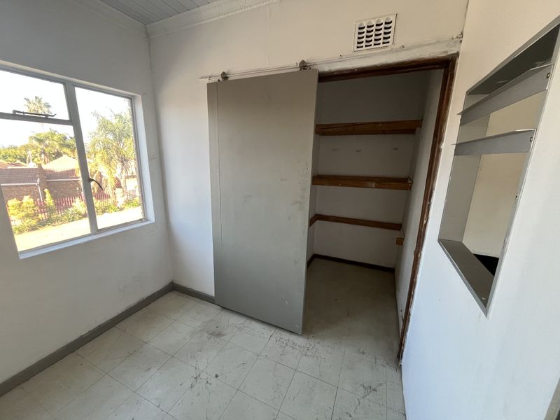 A utility or storage space featuring a sliding door, built-in shelving, and tiled flooring, suitable for use as a pantry or storage area.