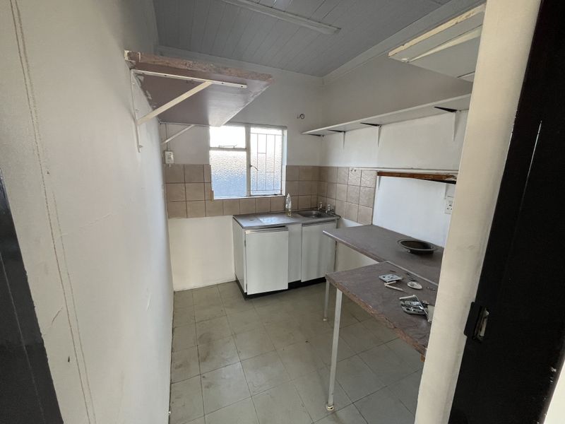 A functional scullery area featuring a stainless steel sink, tiled splashback, and built-in shelving, providing a practical space for utility and prep work.