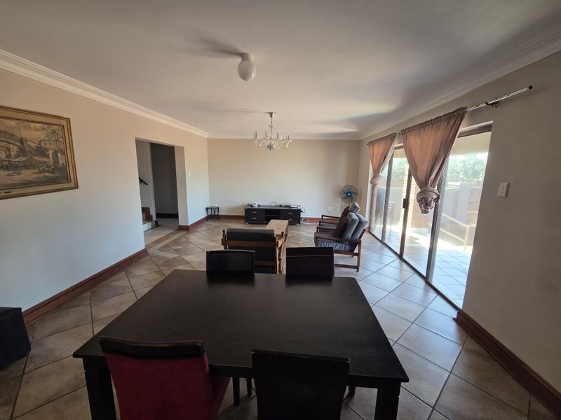 Spacious open-plan living and dining area featuring tiled flooring, crown molding, and large sliding glass doors providing access to the outdoor space.