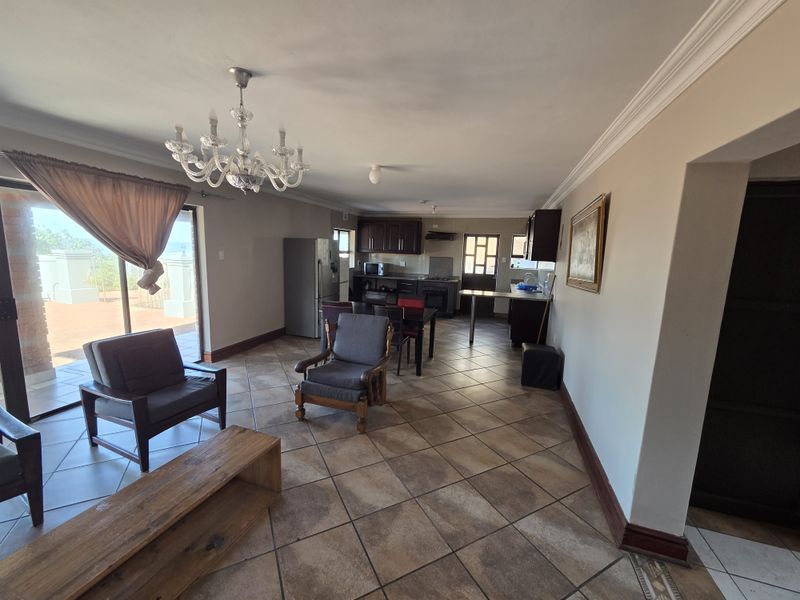 Spacious open-plan living and kitchen area featuring ceramic tile flooring, crown molding, and direct access to an outdoor patio through sliding glass doors.