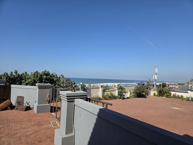 Spacious outdoor paved patio area featuring masonry boundary walls and ocean views, suitable for an office break or outdoor workspace.