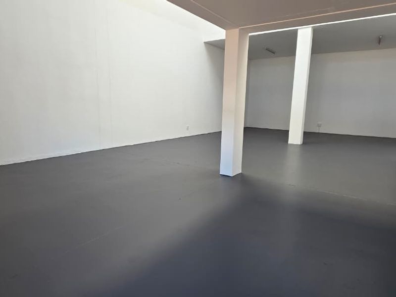 Spacious industrial utility area featuring durable epoxy flooring, support columns, and a metal staircase leading to an upper level.