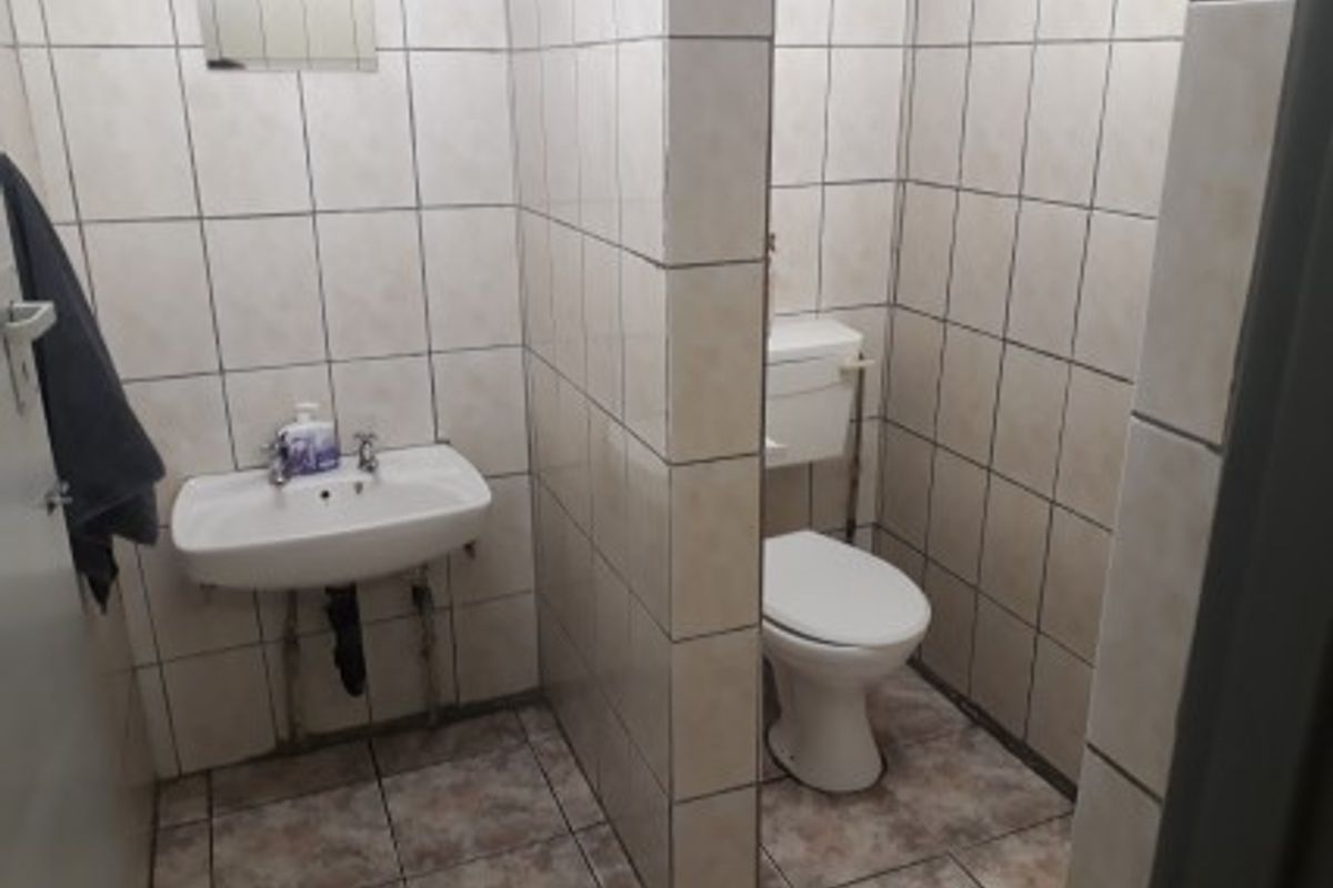 A functional bathroom featuring a wall-mounted basin and a separate toilet cubicle with full-height wall tiling.