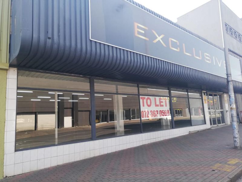Street-level commercial storefront featuring large display windows, metal cladding, and prominent signage, suitable for retail or office use.