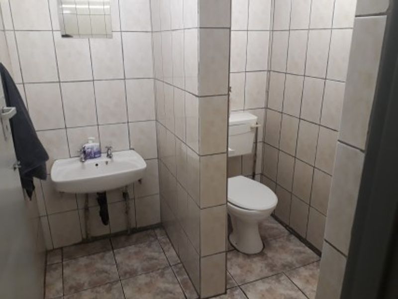 A functional bathroom featuring a wall-mounted basin and a separate toilet cubicle with full-height wall tiling.