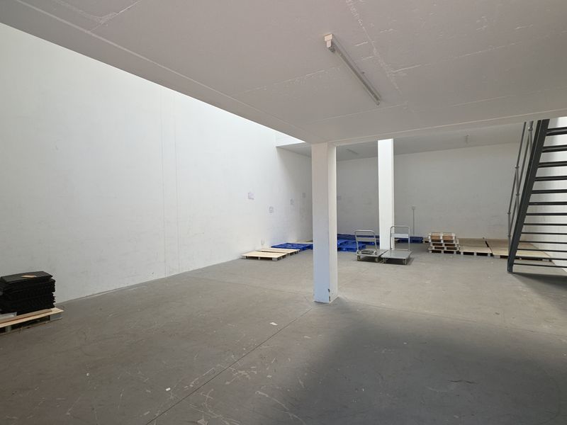Spacious industrial utility area featuring concrete flooring, support columns, and a steel staircase, suitable for storage or workshop use.