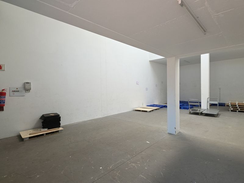 Spacious industrial utility area featuring concrete flooring, structural support columns, and essential fire safety equipment, suitable for storage or light industrial operations.