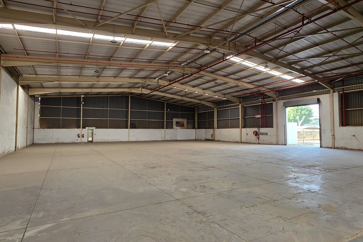 Spacious industrial warehouse featuring a high-clearance steel portal frame, concrete flooring, integrated fire sprinkler system, and natural light via roof skylights.