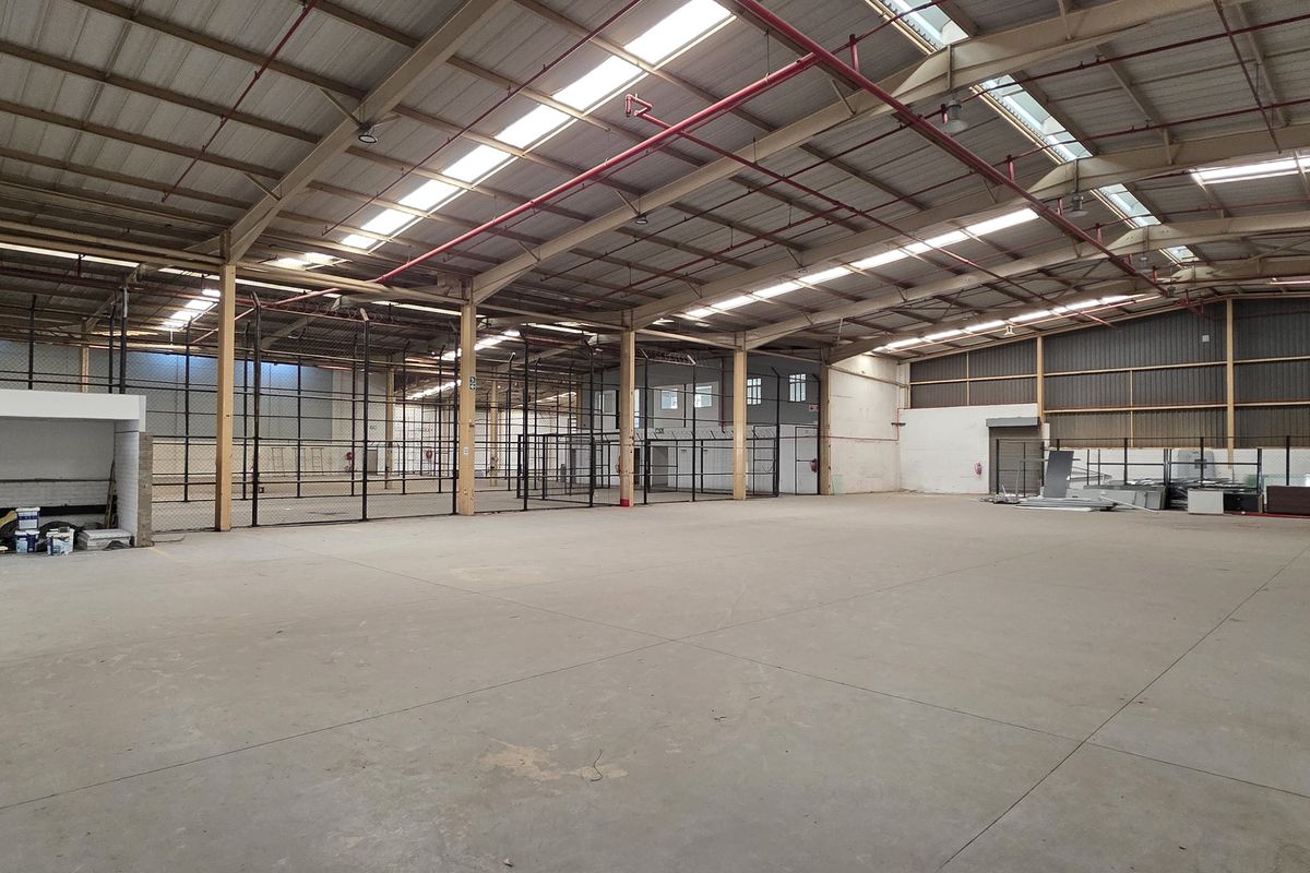 Spacious industrial warehouse featuring high ceilings, concrete flooring, integrated fire sprinkler system, and natural light through roof skylights.