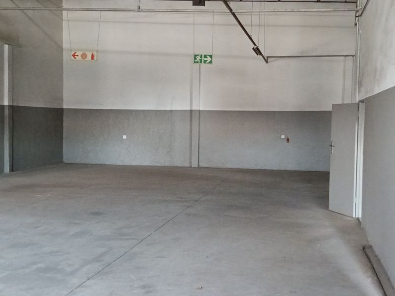 Spacious industrial utility area featuring concrete flooring, exposed ceiling structure, and essential fire safety equipment, suitable for storage or workshop use.