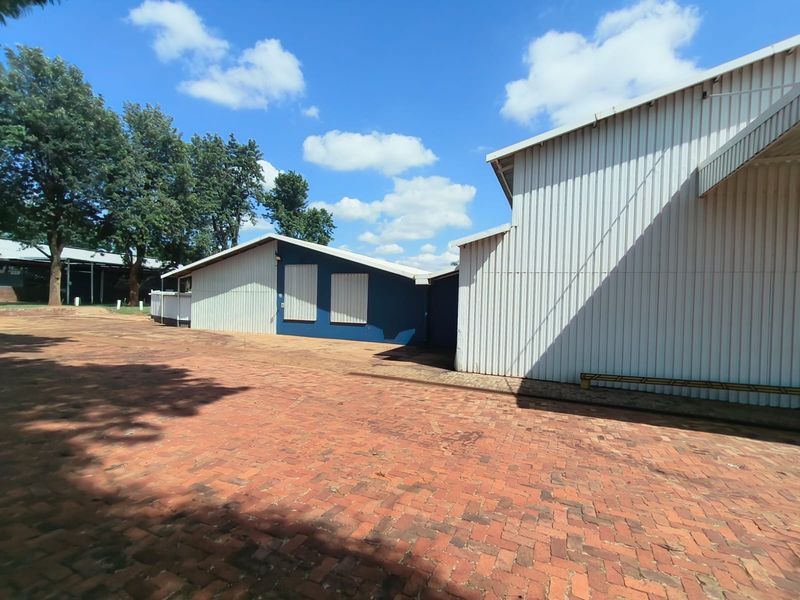 Exterior view of industrial warehouse buildings featuring corrugated metal cladding and a paved brick courtyard area.