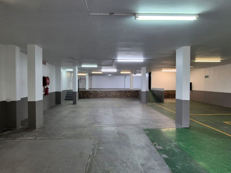 Spacious industrial garage area featuring concrete flooring, painted floor markings, support columns, and integrated fluorescent lighting.