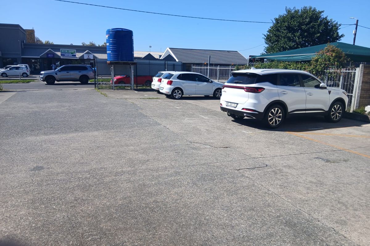 Commercial property exterior featuring a paved parking area, perimeter fencing, and a large water storage tank.