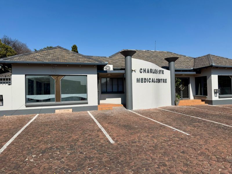 Front exterior view of the Charles Str Medical Centre featuring a paved parking area, tiled roof, and prominent building signage.
