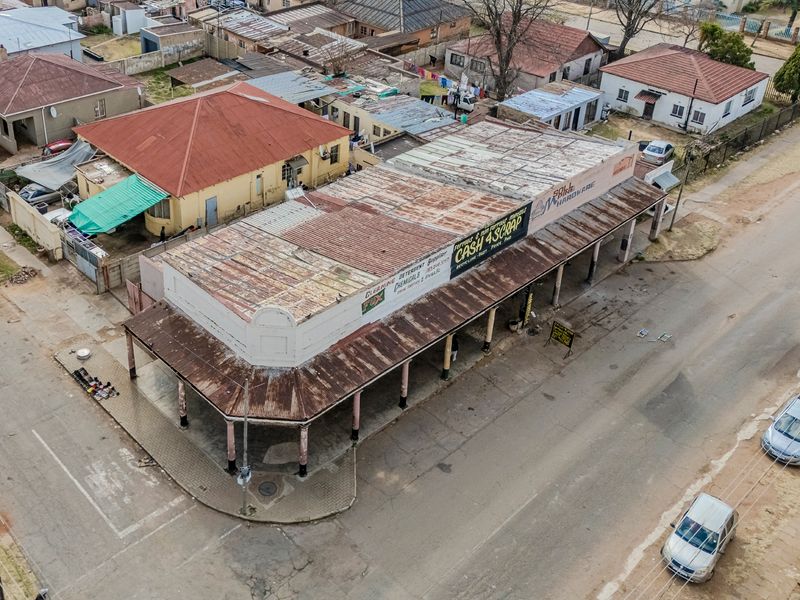 Aerial view of a commercial office building featuring a corrugated metal roof, covered veranda with support columns, and street-level access.