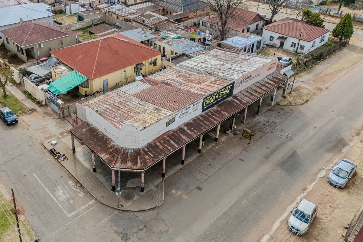 Aerial view of a commercial office building featuring a corrugated metal roof, covered veranda with support columns, and street-level access.