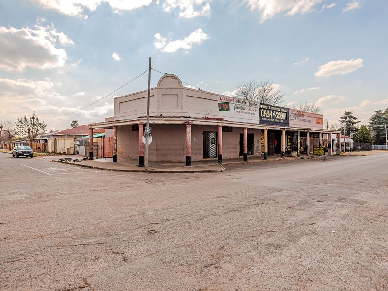 A corner commercial office building featuring a covered veranda with support columns, situated at a street intersection.