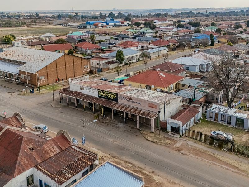 Aerial view of a commercial office and retail property situated in a suburban neighborhood, featuring corrugated metal roofing and street-level access.