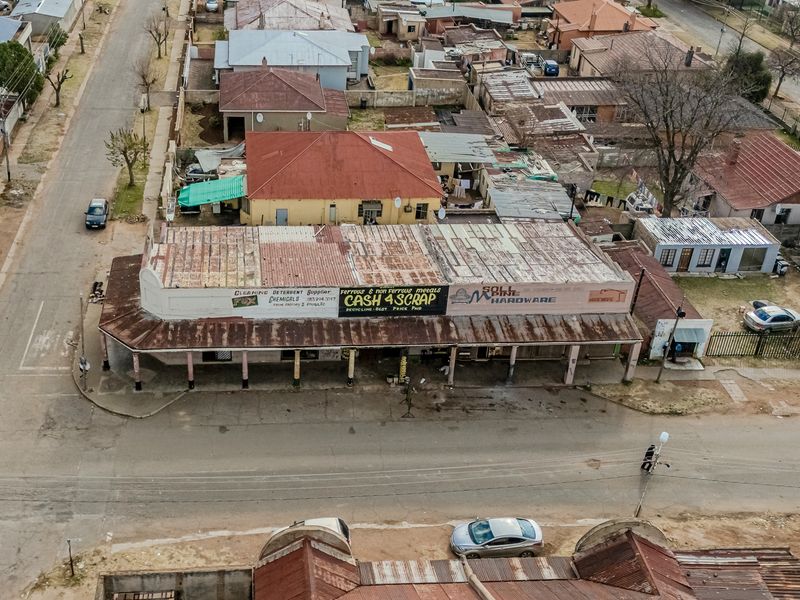 Aerial view of a commercial office and retail building featuring a corrugated metal roof and a covered street-level veranda.