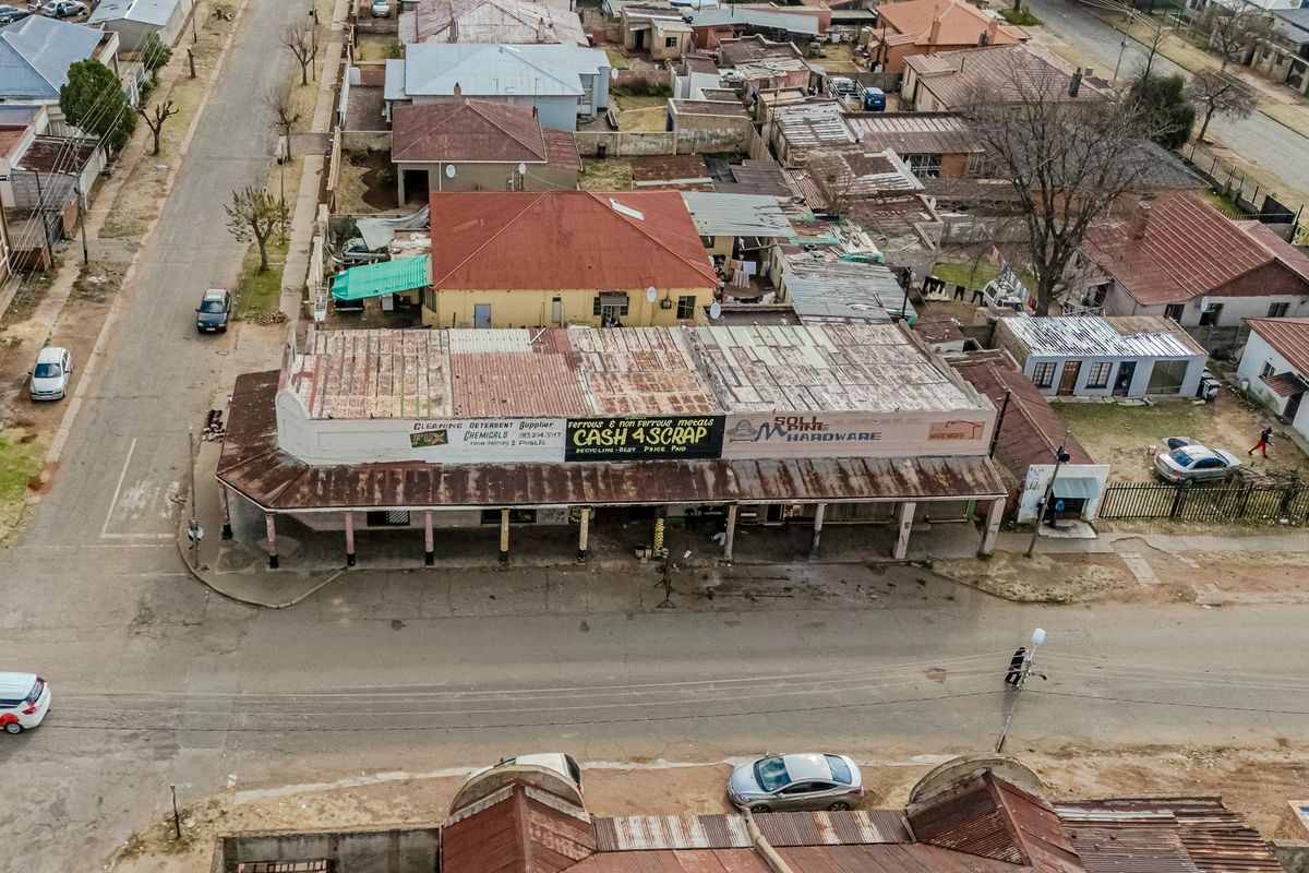 Aerial view of a commercial office and retail building featuring a corrugated metal roof and a covered street-level veranda.