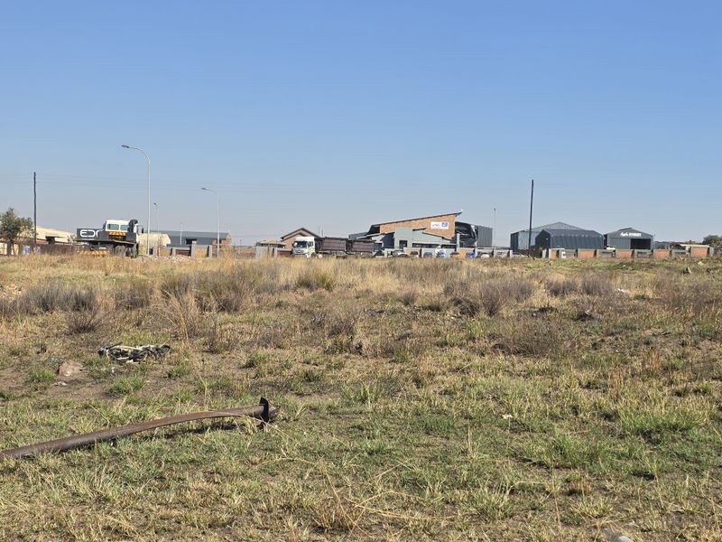 A view of a vacant commercial plot of land with surrounding industrial buildings in the background.