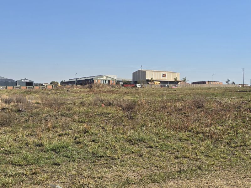 A view of a vacant commercial land plot with surrounding industrial buildings in the background.
