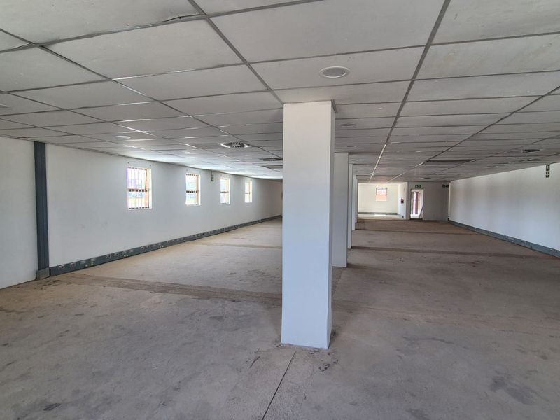 A large, open-plan office space featuring a suspended ceiling, recessed lighting, and structural columns, currently in a shell condition ready for fit-out.