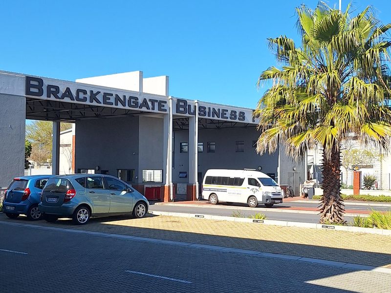 Entrance view of Brackengate Business Park featuring a paved driveway and prominent signage under a clear blue sky.