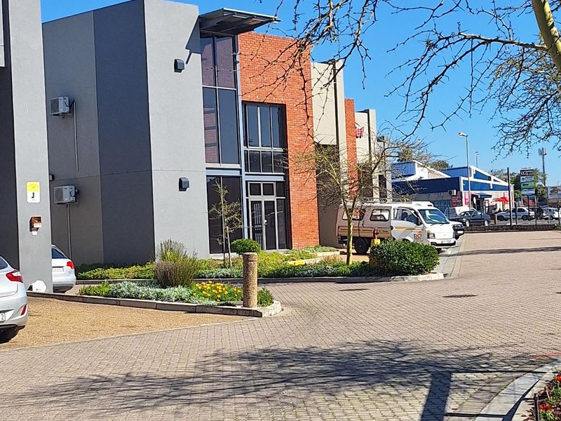 Front exterior view of a modern commercial building featuring a combination of brick and plastered finishes with paved driveway access.