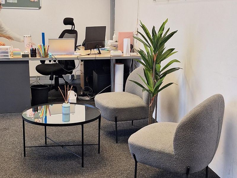 A professional commercial office space featuring carpeted flooring, a suspended ceiling with recessed lighting, and wall-mounted company branding.