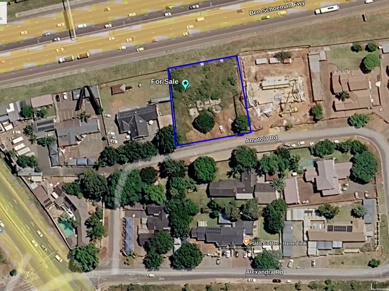 Aerial view of a vacant commercial land plot situated near a major highway and local road infrastructure.