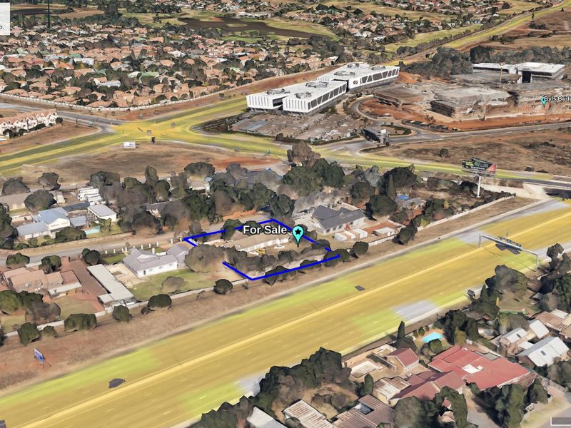 Aerial view of a commercial vacant land plot situated with direct highway frontage in a developed urban area.