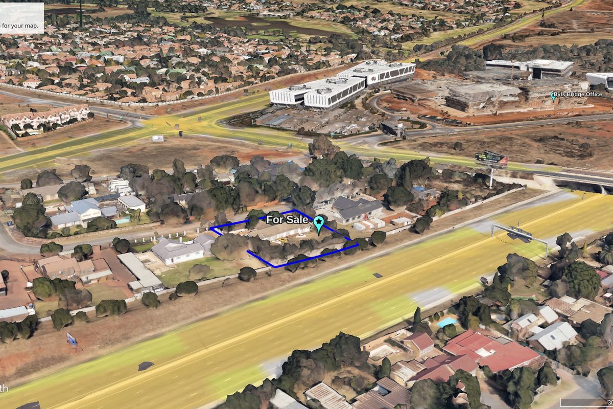 Aerial view of a commercial vacant land plot situated with direct highway frontage in a developed urban area.