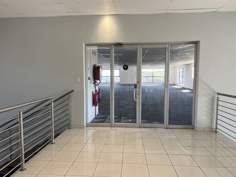 A bright, vacant office suite entrance featuring glass doors, tiled flooring, and integrated fire safety equipment, ready for professional fit-out.