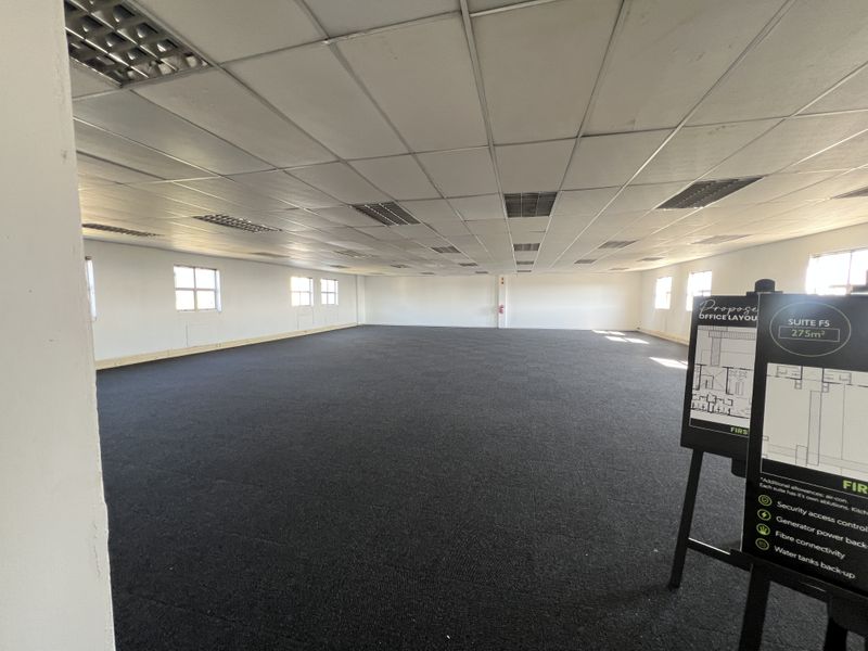 A spacious, open-plan office suite featuring a suspended ceiling, recessed lighting, and dark carpeting, offering a versatile workspace ready for custom fit-out.