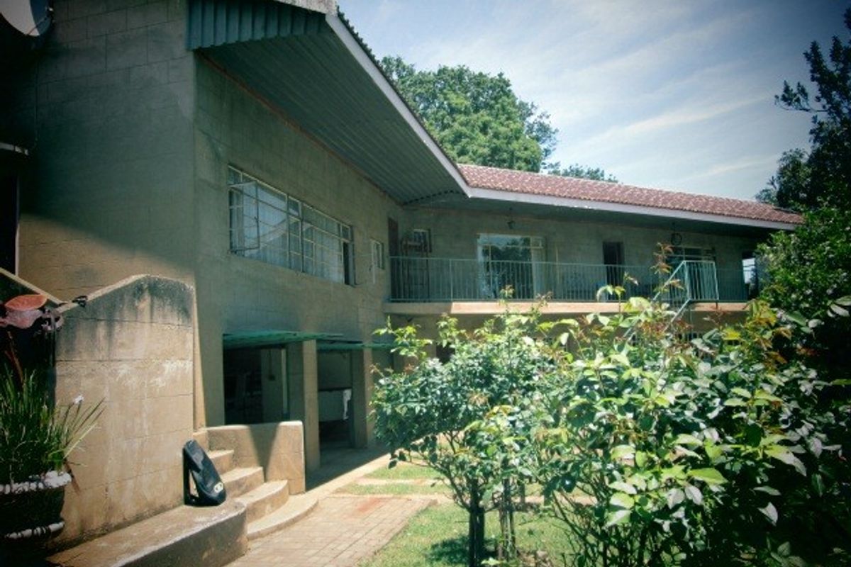 Rear view of the farm property featuring a balcony, concrete staircase, and paved walkway leading to the garden area.