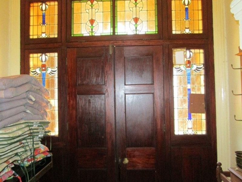 An entrance area featuring traditional timber double doors with decorative stained glass sidelights and transom windows.