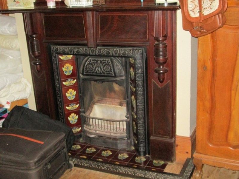 A classic living room featuring an ornate timber fireplace mantel with decorative cast iron insert and period-style ceramic tile detailing.