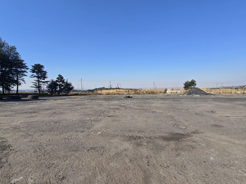 Expansive open industrial yard area with asphalt surfacing, suitable for storage or heavy vehicle maneuvering.