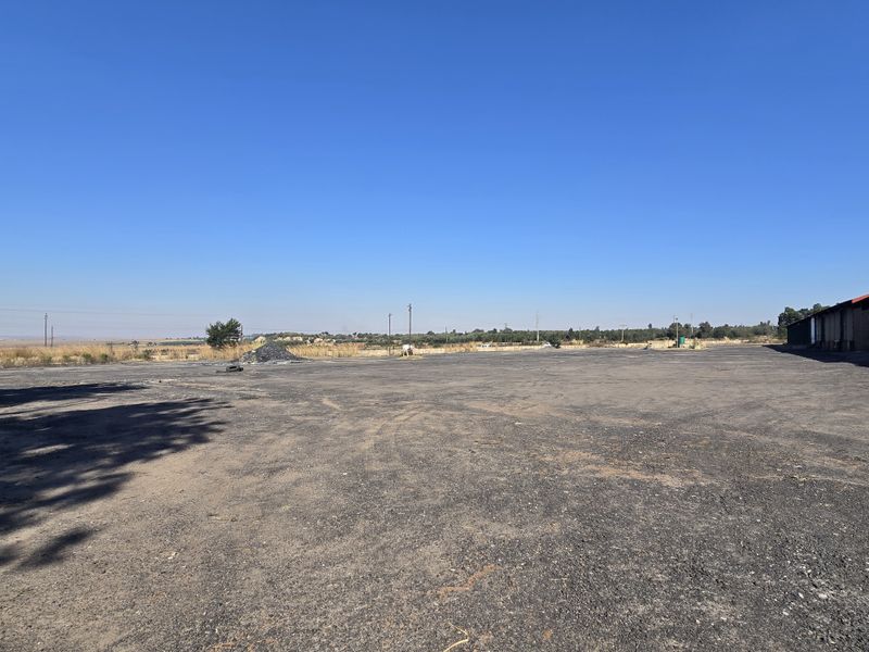 Expansive open-air industrial yard featuring a large asphalt surface area, suitable for heavy vehicle access, storage, or logistics operations.
