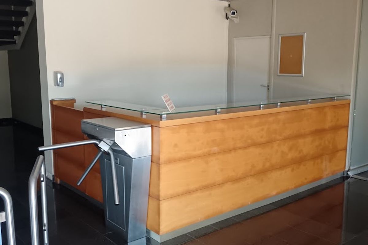 Professional office building entrance featuring a built-in reception desk, security turnstile, and polished tiled flooring in a clean, functional lobby space.