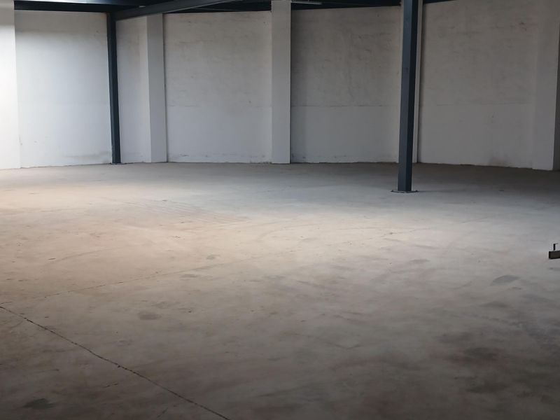 A spacious, empty industrial utility area featuring concrete flooring and exposed steel structural support beams, suitable for various commercial or storage applications.
